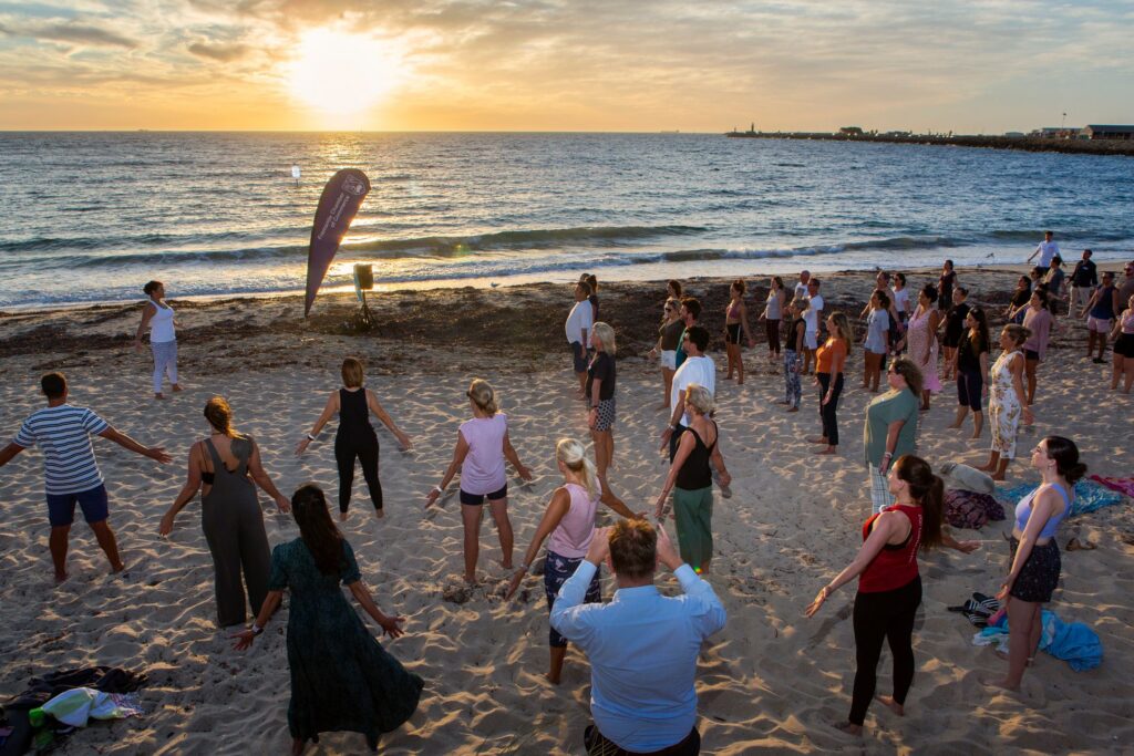 Workplace wellbeing yoga event on beach at sunrise